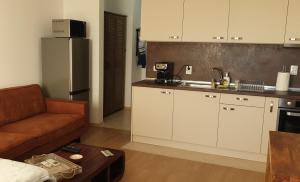a kitchen with white cabinets and a couch in a room at Студио Тони в модерна сграда с фитнес в централна Варна in Varna City