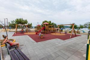 a playground with two swings and a girl laying on a bench at Apartment Nediljka in Vodice