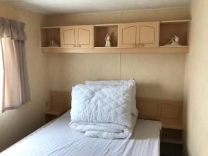a bedroom with a bed with white blankets and shelves at 8 Berth Sunnymede (Atlas) in Ingoldmells