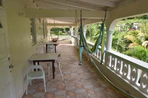 a room with a table and chairs and a balcony at Soufriere Guesthouse in Soufrière