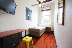 1 dormitorio con cama, escritorio y taburete amarillo en The Nunnery Accommodation, en Melbourne
