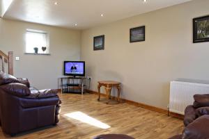 a living room with a couch and a television at Aunt Rachel's Cottage in Bushmills