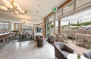 an open living room with chairs and tables and a large window at The Hotel Nelson in Nelson