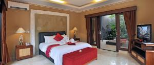 a bedroom with a large bed and a television at Bali Aroma Exclusive Villas in Seminyak