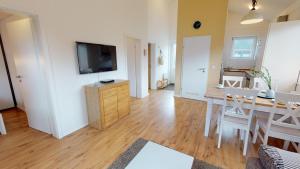 a living room with a dining room table and a television at Feriendorf Südstrand Haus 40 in Pelzerhaken