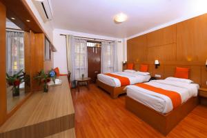 two beds in a hotel room with wood paneling at Hotel Mums Home in Kathmandu