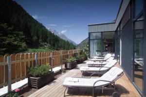 a row of chaise lounges on a wooden deck with mountains at Wellness Spa Pirmin Zurbriggen in Saas-Almagell