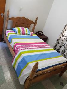 ein Holzbett mit einer bunten gestreiften Bettdecke in einem Zimmer in der Unterkunft Big House Medellin in Medellín