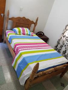a wooden bed with a colorful striped comforter in a room at Big House Medellin in Medellín