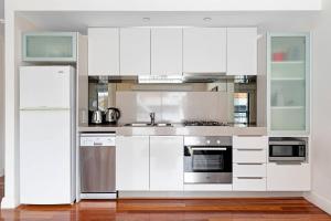 cocina con armarios blancos y nevera en Parklane Apartments, en Fremantle