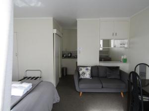 a living room with a couch and a kitchen at Anchorage Motel in Whitianga