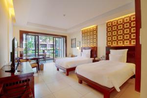 a bedroom with two beds and a desk and a piano at Pullman Sanya Yalong Bay Villas & Resort in Sanya