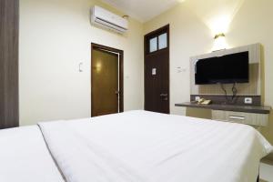 a bedroom with a white bed and a flat screen tv at Hotel Istana Bungur in Jakarta