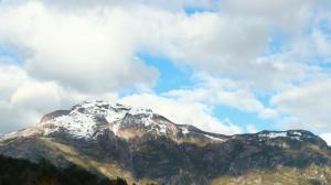 una montaña cubierta de nieve y nubes en el cielo en Cabañas Aitue, en Futaleufú