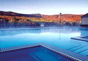 uma grande piscina de água azul com montanhas ao fundo em Killington Grand Resort Hotel em Killington