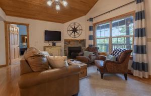 a living room with leather furniture and a tv at Paradise Lodge Home in Branson West
