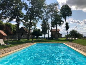 ein Schwimmbad mit einem Haus im Hintergrund in der Unterkunft L'evidence in Bragny-sur-Saône