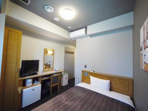 a room with a bed and a desk and a television at Hotel Route-Inn Nago in Nago