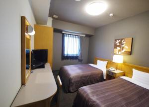 a hotel room with two beds and a television at Hotel Route-Inn Nago in Nago