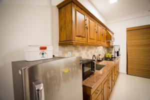 a kitchen with wooden cabinets and a stainless steel refrigerator at Kozy B&B in Mount Lavinia