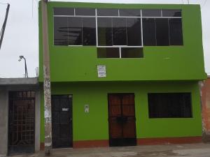 a green building with two doors and windows at Hospedaje Arana in Chincha Alta