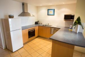 een keuken met een witte koelkast en een wastafel bij Northpoint Holiday Apartments in Alexandra Headland