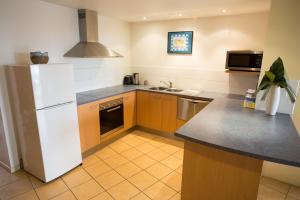 a kitchen with a white refrigerator and a sink at Northpoint Holiday Apartments in Alexandra Headland