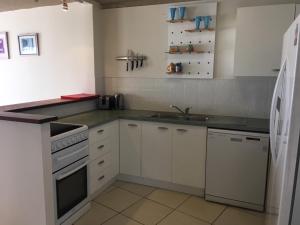 a kitchen with white cabinets and white appliances at Northpoint Holiday Apartments in Alexandra Headland