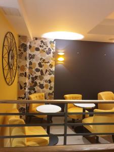 a room with yellow chairs and tables and a wall at Panam Hotel PARIS GAMBETTA- Place Gambetta-Mairie du 20 emme in Paris