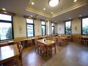 a restaurant with wooden tables and chairs and windows at Hotel Route-Inn Kakegawa Inter in Kakegawa