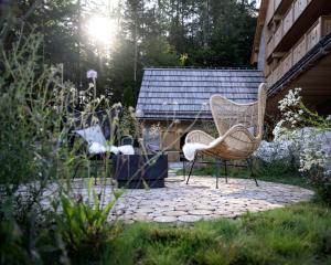 two chairs sitting on a patio in a garden at Boutique hotel Vila Planinka in Zgornje Jezersko
