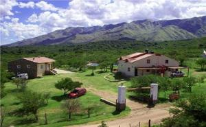 uma casa e um carro num campo com montanhas em Cabañas La Casa de Adriana em Merlo