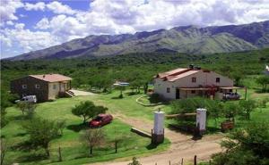 a house and a car in a field with mountains at Cabañas La Casa de Adriana in Merlo