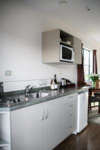 a white kitchen with a sink and a microwave at Carrick Lodge Motel in Cromwell