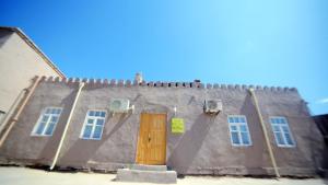 a building with a brown door and two windows at Qutlug Qadam Guest House in Khiva