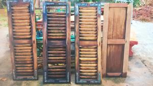 a group of four wooden doors and stairs at Vanpila in Savannakhet