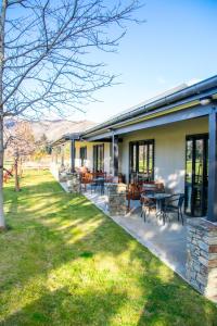 a house with a patio with tables and chairs at Carrick Lodge Motel in Cromwell