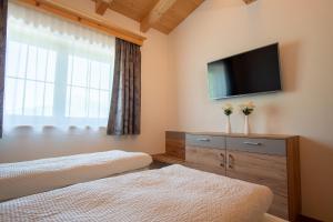 a bedroom with two beds and a flat screen tv at Hof Zenzern in Kitzbühel