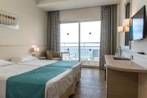 a hotel room with two beds and a large window at Cynthiana Beach Hotel in Paphos