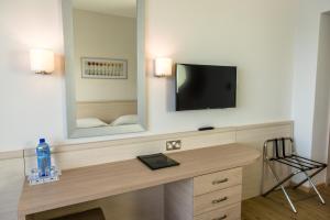 een kamer met een bureau, een televisie en een spiegel bij Cynthiana Beach Hotel in Paphos City