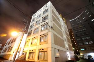 a tall white building on a city street at night at KIYAZA City Sapporo in Sapporo