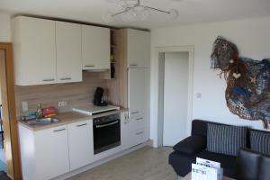 a kitchen with white cabinets and a couch in a room at Bauernhof Schink in Zell am Moos