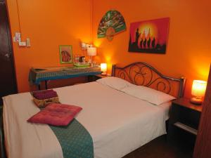 ein Schlafzimmer mit einem großen weißen Bett und einer orangefarbenen Wand in der Unterkunft Meechok Home in Chiang Mai