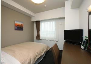 Habitación de hotel con cama y TV de pantalla plana. en Hotel Route-Inn Handakamezaki, en Handa