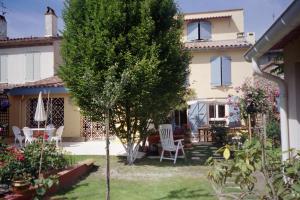 a house with a yard with chairs and a tree at La Cognée in Cugnaux