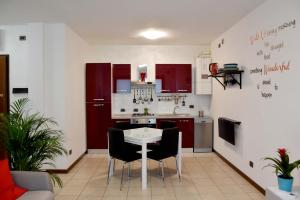 uma cozinha com armários vermelhos e uma mesa e cadeiras brancas em Appartamento CA TIZIANA 2 "Wonderful" di Tiziana - Venezia - Jesolo beach em Musile di Piave