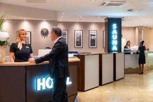 Ein Mann und eine Frau stehen an einem Hotelschalter in der Unterkunft Mauritius Hotel & Therme in Köln + 37 Fotos
