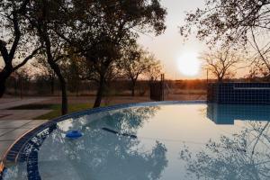 a swimming pool with the sunset in the background at Cottage Lenise in Phalaborwa