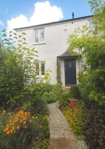a white house with a brick path in front of it at Mulberry cottage in Cheltenham