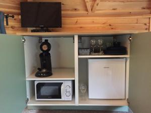 a cabinet with a microwave and a tv on top at La cabane de l'Atelier in Bomal